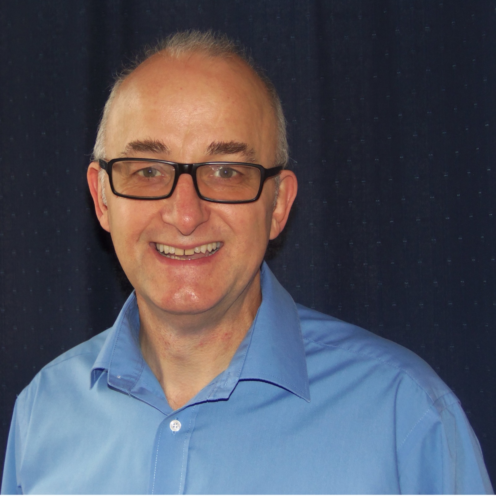 Man in blue open-neck shirt with glasses